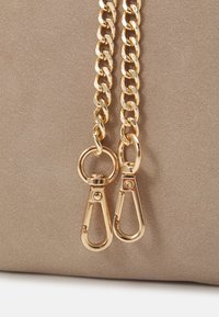 Brązowa torba o gładkiej fakturze, wyposażona w dwa złote łańcuszki i zapięcia na klipsy, podkreślająca wypolerowane detale z metalu.
