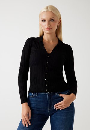 Top lungo a maniche nere a costine con scollatura a V e chiusura con bottoni. Presenta un colletto e un tessuto a maglia testurizzato.