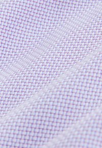 Textilstoff mit einem gewebten Muster in Hellviolett und Weiß. Zeigt eine gitterartige Struktur mit sichtbaren verflochtenen Fäden.