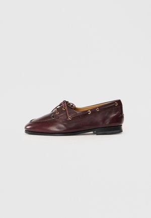 Burgundy leather boat shoe with a rounded toe, decorative stitching, gold eyelets, and laces. Flat heel and smooth texture.