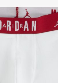Fehér boxer alsó, piros elasztikus derékpánttal, amelyen fehér "AIR JORDAN" logó és sziluett található. Sima tapintású, standard szabású dizájn.