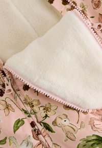 Roosa kangas lillemustrite ja loomade illustratsioonidega, pehme valge fliisvoodriga ja tõmblukuavaga.