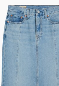 Jupe en denim bleu clair à coupe droite, dotée de deux poches avant, d'une couture centrale apparente et d'accents métalliques de couleur cuivre.