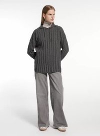 Szary sweter z prążkowanej tkaniny z kapturem, z zapięciem na guziki pod szyją i długimi rękawami, w zestawie z jasnoszarymi spodniami o szerokich nogawkach.
