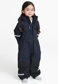 Laivastonsininen vedenpitävä haalari mustilla yksityiskohdilla; varustettu hupulla, heijastinliuskoilla ja joustavilla hihansuilla. Suunniteltu kylmälle säälle.