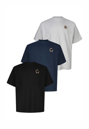 Tre enkle t-skjorter med korte ermer i svart, marineblå og grå, hver med et lite brodert gullklenodium på øvre venstre bryst.