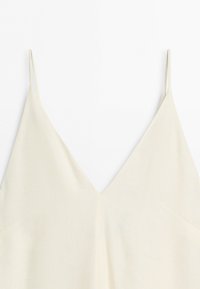 Cream-colored sleeveless top with thin spaghetti straps and a V-shaped neckline on a white background.