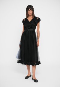 Rochie neagră cu dantelă florală la guler și margine, cu un corset ajustat, fustă din tul fluid și un brâu din satin negru.