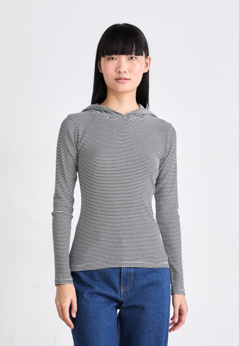 Svarte og hvite stripete langermede topper med hette, laget av lett stoff, figursydd design, kombinert med blå denimjeans.