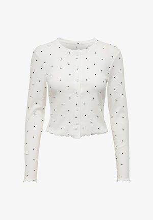 Gilet blanc à manches longues avec des pois noirs, col rond, fermeture à boutons sur le devant et ourlet festonné. Matière douce et extensible.