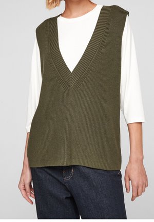 Gilet en maille vert olive avec un décolleté en V profond et une texture côtelée, porté sur une chemise blanche à manches longues, associé à un jean foncé.