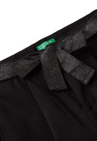 Czarny materiałowy pasek z kokardą, wykonany z teksturowanego, błyszczącego materiału. Widoczna zielona metka z napisem "United Colors of Benetton".