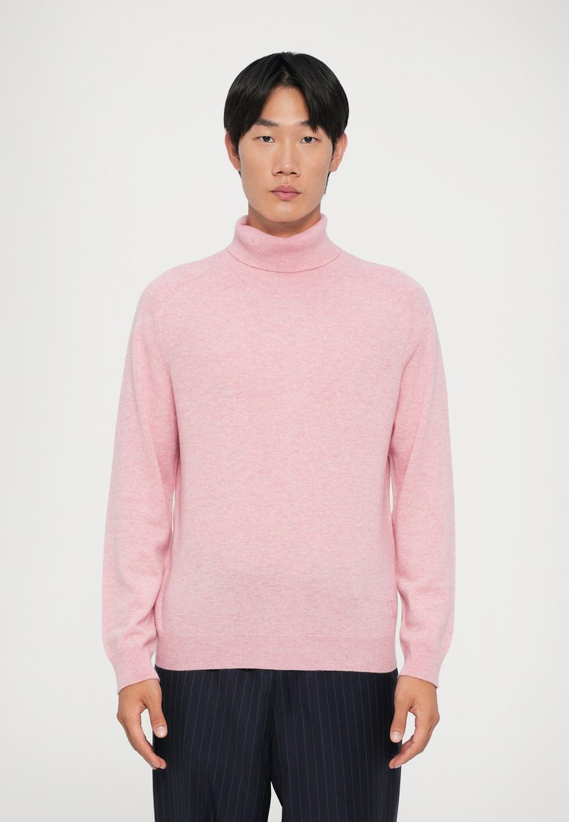 Maglione rosa a collo alto in morbido tessuto, con maniche lunghe, colletto a costine e una vestibilità aderente, abbinato a pantaloni navy a righe sottili.