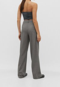 Szare szerokie spodnie o dopasowanym kroju, wykonane z gładkiego materiału, z wysokim stanem i subtelnym wykończeniem szwu z tyłu, zestawione z dopasowanym topem na ramiączkach.
