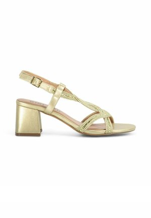 Sandal de talón bajo en dorado con diseño de tiras entrecruzadas con acentos metálicos y un material superior liso y brillante.