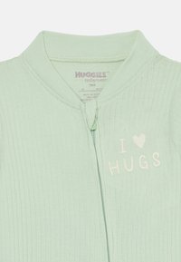 Mintgrønn ribbestrikket bomullsnattdrakt til barn med glidelås, med brodert tekst "I ❤️ HUGS" i hvitt foran.