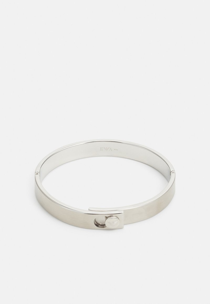 Silverfärgad metallarmband med en slät, polerad yta och ett cirkulärt låsdetalj. Har en enkel, minimalistisk design.