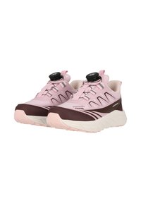 Een paar waterdichte softshell sneakers in roze en kastanjebruin met witte zolen en een zwart draaiknopvetersysteem, zijwaarts weergegeven.