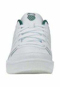 Tenisi atletici albi cu accente verzi, din material sintetic de piele, vârful rotund, design cu șireturi și o etichetă cu logo pe limba pantofului.