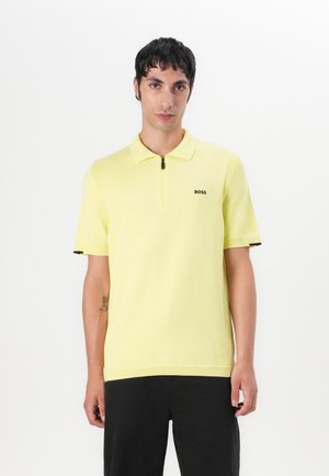 Yellow polo shirt with a zip collar, short sleeves, and black accents on cuffs. Features a small black "BOSS" logo on the chest.