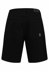 Shorts noirs avec deux poches arrière, dont une présentant un petit logo géométrique blanc sur le bas côté droit.