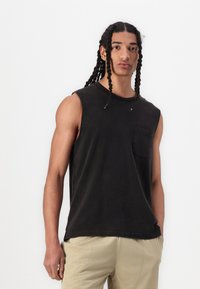 Sort, ærmeløs cottontanktop med rund hals og en brystlomme. Har en afslappet pasform og blødt, tekstureret stof.