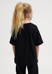 Schwarzes Baumwoll-T-Shirt mit kurzen Ärmeln, lockerer Passform und Rückansicht. Glatte Textur, Rundhalsausschnitt und minimalistisches Design.