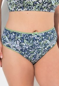 Combinazione intima a vita alta con motivo floreale in blu navy, verde e bianco. Presenta un bordo elastico verde e un piccolo dettaglio a fiocco nella parte anteriore.
