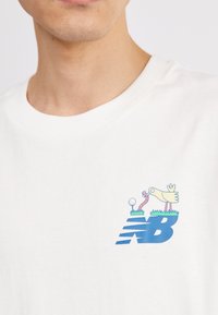 New Balance ATHLETICS RELAXED GOLF CARTOON - Apdrukāts T-krekls - sea salt
