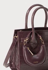 Sac à main texturé de couleur violet foncé avec des anses supérieures, une sangle amovible et une petite pochette en croissant assortie attachée avec des accessoires en or.
