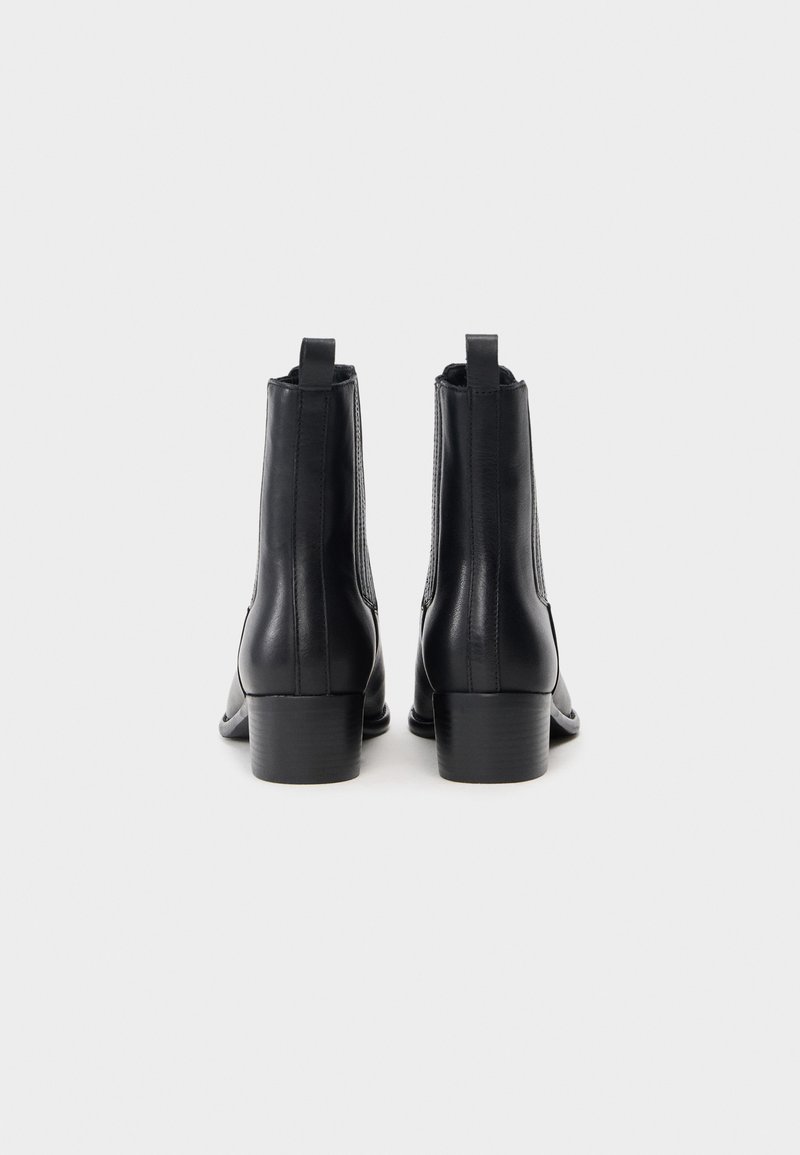 Schwarze Lederstiefeletten mit einer glatten Oberfläche, elastischen Seitenpaneelen, kurzem Blockabsatz und einer Schlaufe hinten für ein einfaches Anziehen.