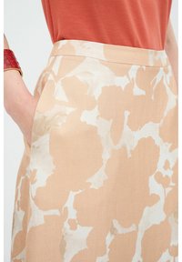 Gonna beige con motivi floreali crema chiaro, dotata di una cintura elastica, texture del tessuto morbida e tasche laterali.