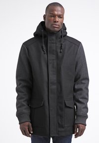 Schwarze Kapuzenparka aus einer Kombination aus glattem und strukturiertem Stoff, mit Fronttaschen und verstellbaren Kordeln an der Kapuze.