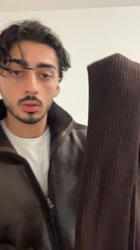 Smeđa rebrasta marama izrađena od mekanog materijala, držana uz tamnu jaknu. Marama ima teksturiranu površinu i vertikalni uzorak.