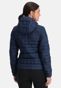 Marine blauwe gewatteerde pufferjack met een capuchon. Voorzien van een diamantpatroon, elastische manchetten en een getailleerde pasvorm, gemaakt van lichtgewicht, waterafstotend materiaal.