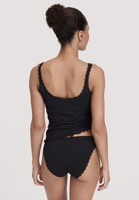 Zwarte katoenen tanktop met gegolfde kantafwerking, gecombineerd met bijpassende zwarte hoge slip. Vlotte textuur, slim fit ontwerp en minimalistische stijl.
