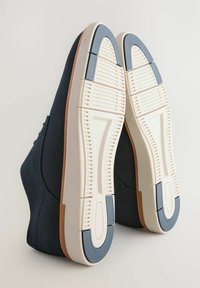 Sneaker navy blu con tomaia in tessuto texturizzato e suola in gomma bianca; sottili dettagli marrone chiaro vicino al tallone. Battistrada decorato sulla suola.