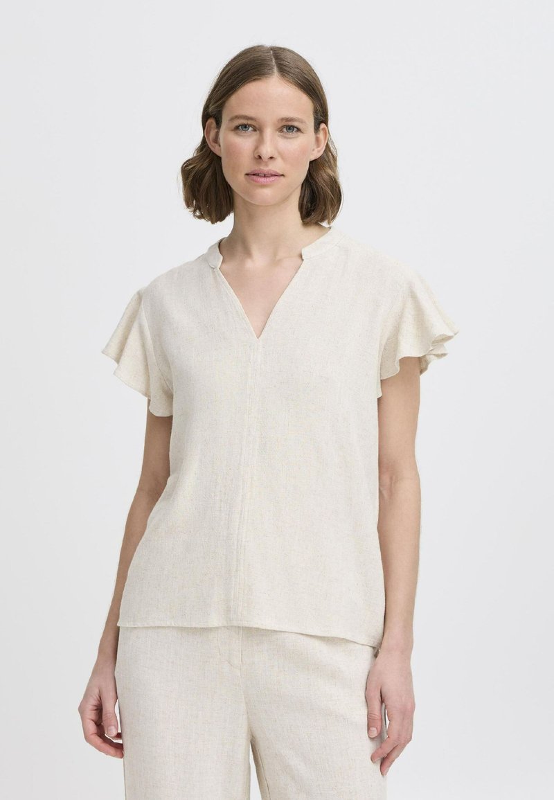 Top corto a maniche corte beige chiaro con scollatura a V e maniche arricciate, realizzato in un tessuto testurizzato. Design a strati che scende leggermente sotto la vita.