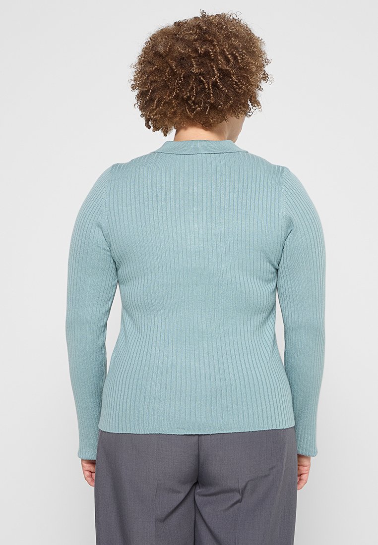 Rippenpullover mit langen Ärmeln aus weichem blauen Strick mit Rundhalsausschnitt, von hinten gezeigt, kombiniert mit grauen Hosen. Glatte Textur, figurbetonter Schnitt.