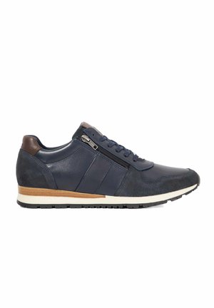 Marineblauwe sneaker met een combinatie van glad en suede leer, vetersluiting met een accentrits, witte tussenzool en een bruine hielafwerking.