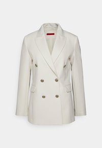 Crème dubbelzijdig blazer met gesneden revers, goudkleurige knopen en voorzakken. Gemaakt van een gladde stof met een op maat gemaakte pasvorm.