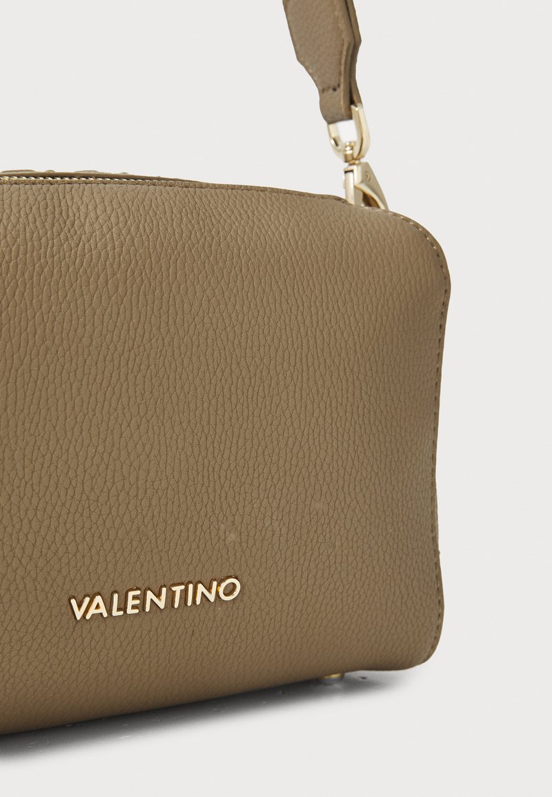 Sac à main en cuir texturé marron avec un logo doré "Valentino" sur le devant. Il dispose d'une bandoulière et d'un design compact.