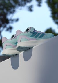 Športové topánky v aqua a levanduľovej farbe s textúrovaným sieťkovým zvrškom, nastaviteľným remienkom a hrubou bielou podrážkou s vzorovaným gripom.