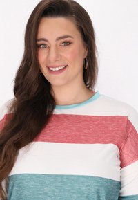 Tricou cu dungi, având culorile roșu, alb și albastru-verde, cu un guler acoperit cu un material texturat de un albastru deschis. Fabricat dintr-un material moale.