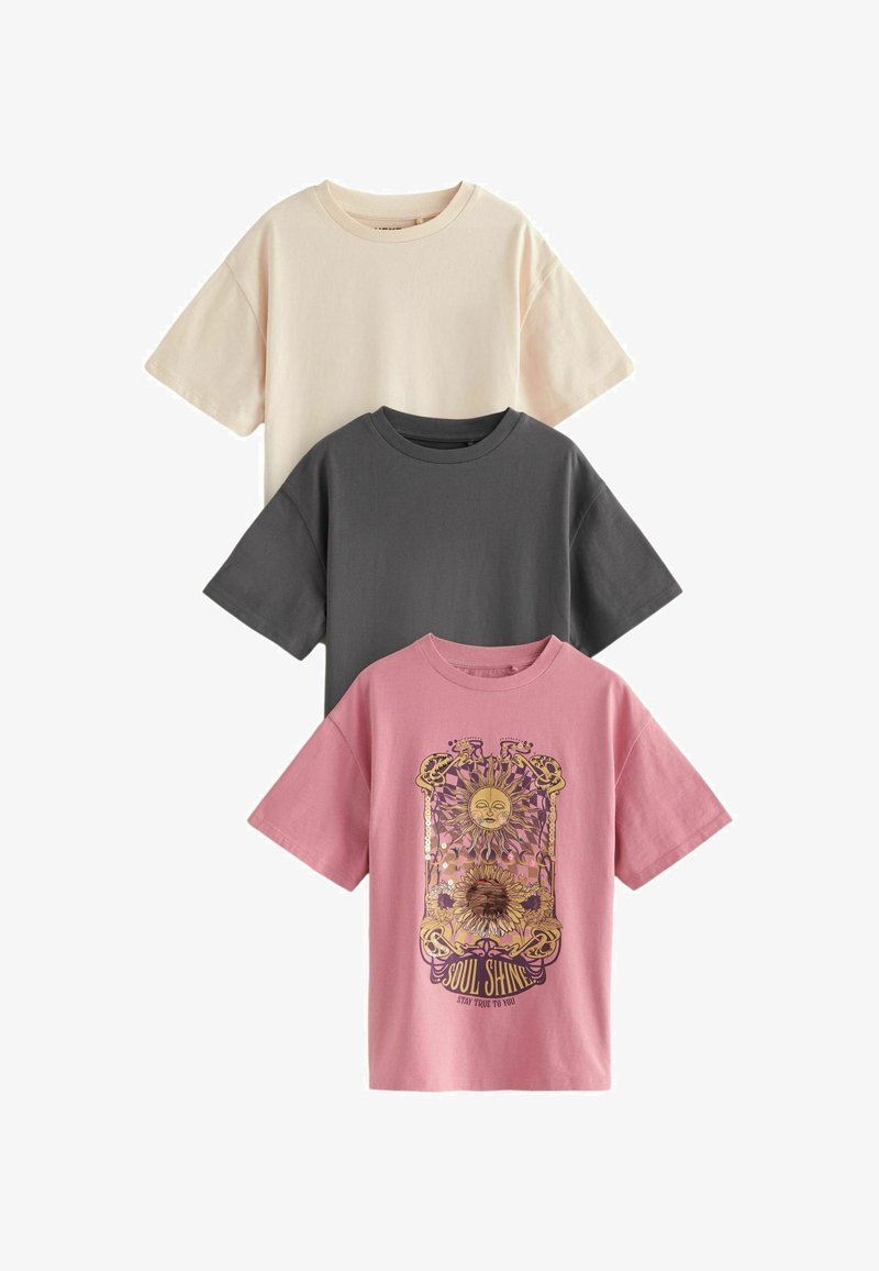 Three cotton t-shirts in beige, charcoal, and pink. The pink shirt features a graphic design with a sun and floral elements.