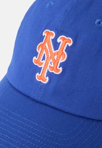 Modrá baseballová čiapka z bavlny s guľatou korunou, s vyšitým vyvýšeným oranžovo-bielym logom "M" na prednej strane.