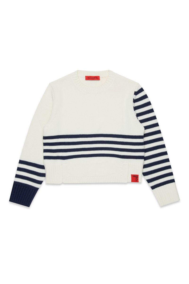 Hvit strikket genser med marineblå striper, rund hals, lange ermer og ribbestrikkede mansjetter. Har en rød etikett nederst til venstre.