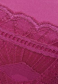 Tissu fuchsia avec des détails en dentelle aux bords festonnés, des motifs texturés et des sections lisses, créant un contraste visuel.