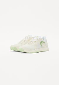 Leichte Sportschuhe mit einem cremefarbenen Obermaterial, Netzpaneelen, grünen Akzenten und einer strukturierten Außensohle für Grip.
