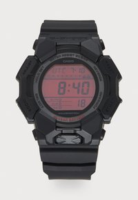 Montre numérique avec boîtier et bracelet en résine noire, écran LCD rouge indiquant l'heure et les fonctions, boutons pour ajuster les paramètres, et résistance à l'eau.